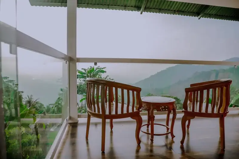 Glass-walled balcony of La Vista Villa overlooking misty hills