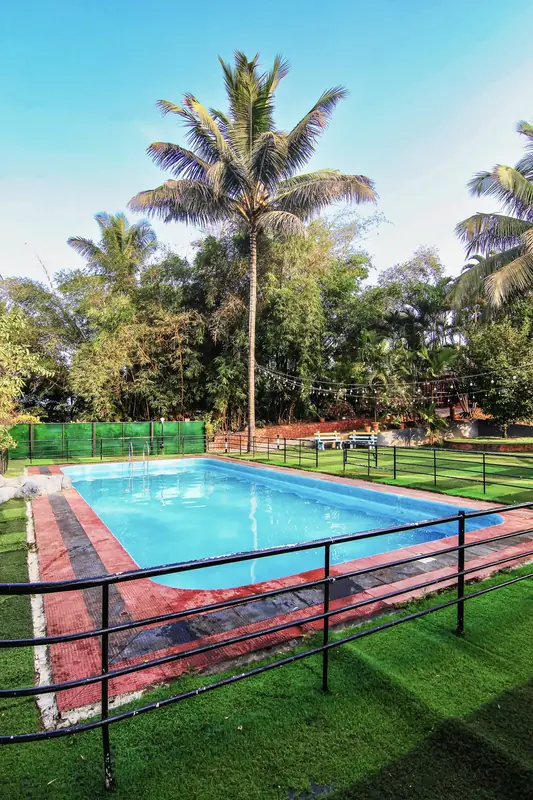 Swimming pool surrounded by coconut palms at Purayil Resort Kakkadampoyil